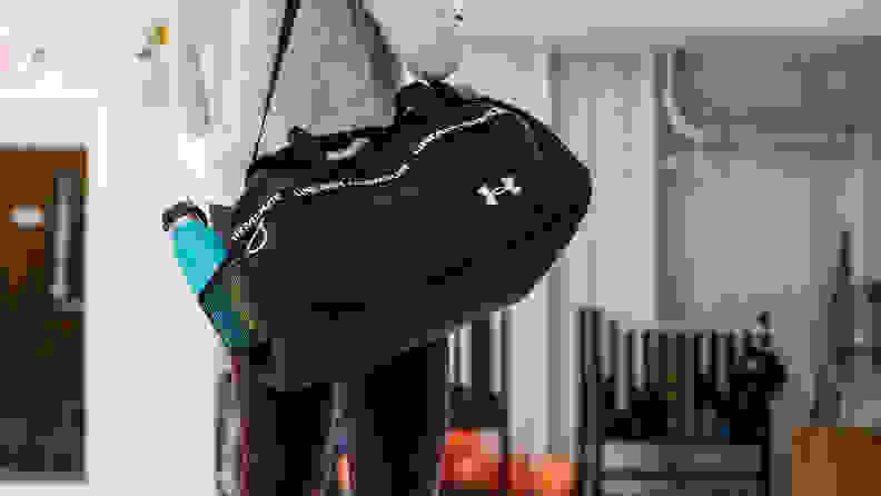 A woman carrying a duffel bag on her shoulder.